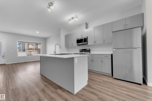 Kitchen with stainless steel appliances, gray cabinets, light wood-style floors, an island with sink, and a textured ceiling - 1235 16 Avenue, Edmonton, AB - Indoor Photo Showing Kitchen