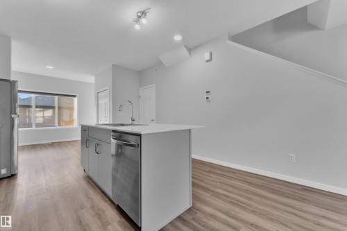 Kitchen with a kitchen island with sink, stainless steel appliances, light wood-type flooring, a textured ceiling, and gray cabinetry - 1235 16 Avenue, Edmonton, AB - Indoor