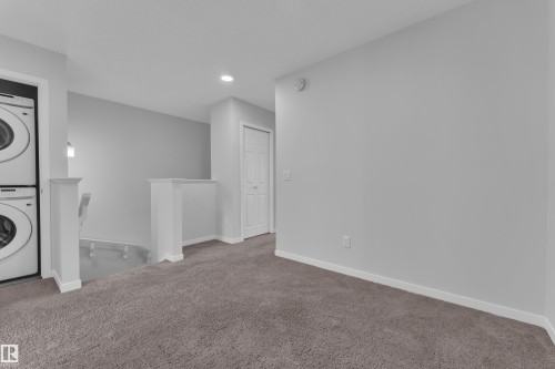 Laundry area featuring stacked washer and clothes dryer, carpet, and recessed lighting - 1235 16 Avenue, Edmonton, AB - Indoor Photo Showing Laundry Room