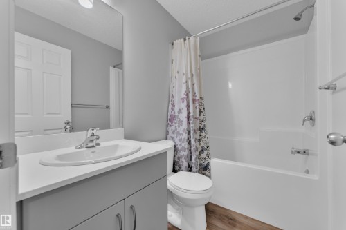 Bathroom with vanity, shower / tub combo with curtain, light wood-style floors, and a textured ceiling - 1235 16 Avenue, Edmonton, AB - Indoor Photo Showing Bathroom