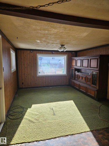 Unfurnished room with a textured ceiling, wood walls, and parquet floors - 5314 57 Street, Cold Lake, AB - Indoor Photo Showing Other Room