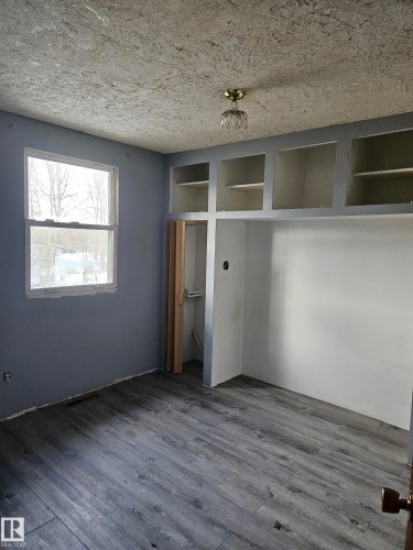 Unfurnished bedroom with dark wood finished floors, a closet, and a textured ceiling - 5314 57 Street, Cold Lake, AB - Indoor