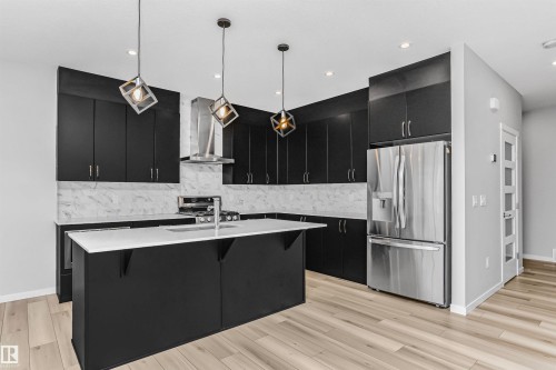 Kitchen featuring dark cabinets, stainless steel appliances, a breakfast bar, and hanging light fixtures - 3108 158 Street, Edmonton, AB - Indoor Photo Showing Kitchen With Stainless Steel Kitchen With Double Sink With Upgraded Kitchen
