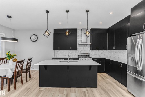 Kitchen featuring dark cabinets, stainless steel appliances, a kitchen island with sink, and hanging light fixtures - 3108 158 Street, Edmonton, AB - Indoor Photo Showing Kitchen With Stainless Steel Kitchen With Upgraded Kitchen
