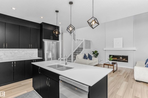 Kitchen with dark cabinets, a kitchen island with sink, open floor plan, and pendant lighting - 3108 158 Street, Edmonton, AB - Indoor Photo Showing Kitchen With Double Sink With Upgraded Kitchen