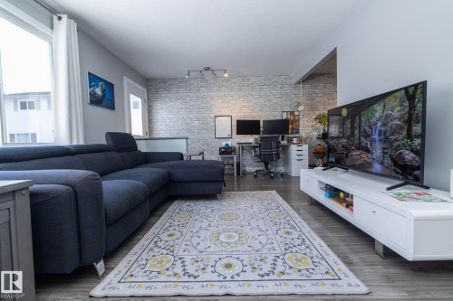 Living area with brick wall, a desk, an accent wall, dark wood finished floors, and track lighting - 4371 46 Street, Stony Plain, AB - Indoor Photo Showing Living Room