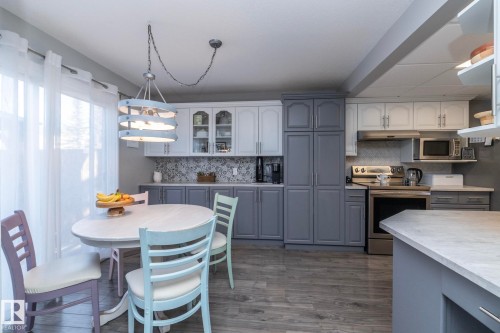 Kitchen featuring gray cabinetry, stainless steel appliances, dark wood finished floors, and glass fronted cabinets - 4371 46 Street, Stony Plain, AB - Indoor