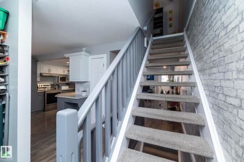 Staircase with brick wall and wood finished floors - 4371 46 Street, Stony Plain, AB - Indoor Photo Showing Other Room