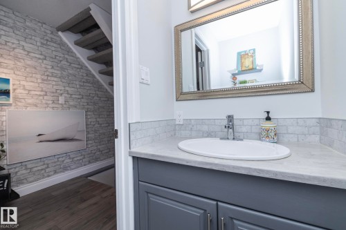 Bathroom with vanity, brick wall, and dark wood-type flooring - 4371 46 Street, Stony Plain, AB - Indoor Photo Showing Bathroom