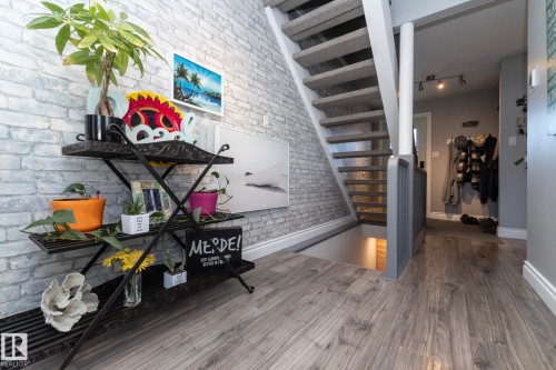 Stairs featuring brick wall, wood finished floors, and track lighting - 4371 46 Street, Stony Plain, AB - Indoor Photo Showing Other Room