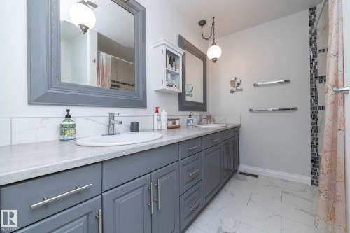 Bathroom featuring double vanity, a shower with curtain, and light marble finish flooring - 4371 46 Street, Stony Plain, AB - Indoor Photo Showing Bathroom