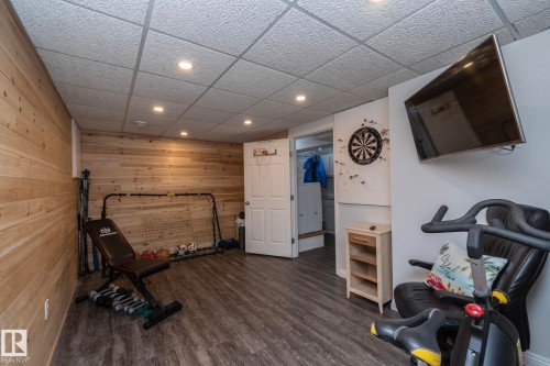 Exercise area with recessed lighting, a drop ceiling, dark wood-type flooring, and wood walls - 4371 46 Street, Stony Plain, AB - Indoor