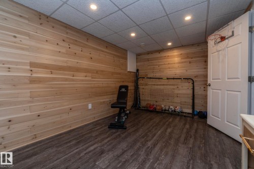 Workout area featuring a drop ceiling, dark wood-style flooring, recessed lighting, and wood walls - 4371 46 Street, Stony Plain, AB - Indoor