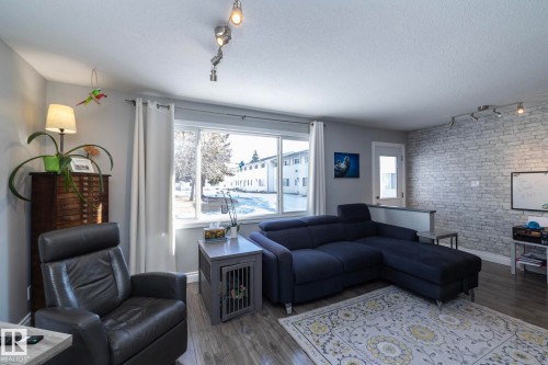 Living area featuring track lighting, a textured ceiling, wood finished floors, and an accent wall - 4371 46 Street, Stony Plain, AB - Indoor Photo Showing Living Room