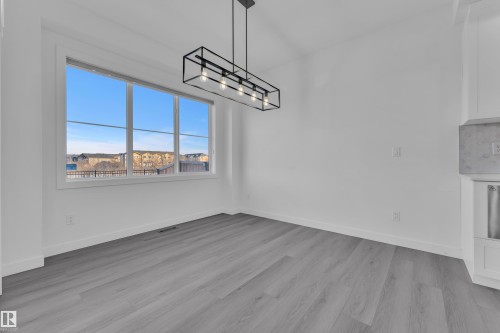 Unfurnished dining area with light wood-style floors and hanging lights - 1822 Collip View View, Edmonton, AB - Indoor Photo Showing Other Room