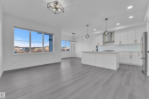 Kitchen with tasteful backsplash, white cabinetry, light countertops, open floor plan, and freestanding refrigerator - 1822 Collip View View, Edmonton, AB - Indoor Photo Showing Kitchen