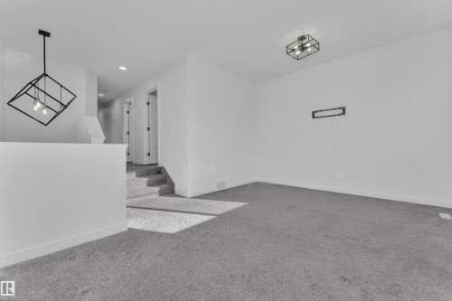 Carpeted spare room featuring a chandelier and baseboards - 1822 Collip View View, Edmonton, AB - Indoor Photo Showing Other Room