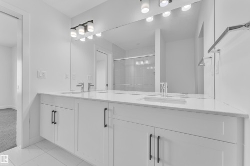 Bathroom featuring double vanity, a shower stall, light colored carpet, and light tile patterned flooring - 1822 Collip View View, Edmonton, AB - Indoor Photo Showing Bathroom