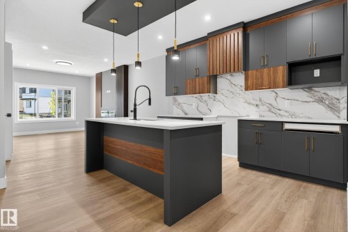 Kitchen featuring modern cabinets, light wood-type flooring, a kitchen island with sink, light stone counters, and two tone cabinetry - 456 Crystal Creek Link, Leduc, AB - Indoor Photo Showing Kitchen With Upgraded Kitchen