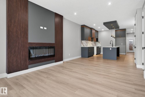 Unfurnished living room featuring a glass covered fireplace, recessed lighting, and light wood-style flooring - 456 Crystal Creek Link, Leduc, AB - Indoor With Fireplace