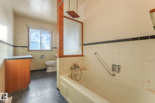 Full bathroom featuring tile walls, wainscoting, dark tile patterned floors, and vanity - 10324 42 Street, Edmonton, AB - Indoor Photo Showing Bathroom