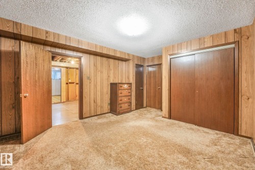 Unfurnished bedroom featuring a closet, carpet floors, a textured ceiling, and wood walls - 10324 42 Street, Edmonton, AB - Indoor Photo Showing Other Room