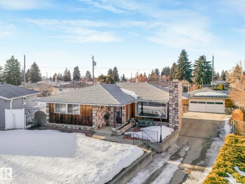 View of front of home with a shingled roof, a gate, stone siding, an outdoor structure, and a garage - 10324 42 Street, Edmonton, AB - Outdoor