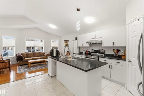 Kitchen featuring an island with sink, stainless steel appliances, light tile patterned floors, open floor plan, and white cabinets - 1706 Turvey Bend, Edmonton, AB - Indoor Photo Showing Kitchen With Double Sink