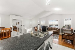 Kitchen featuring open floor plan, light tile patterned flooring, white cabinetry, dishwasher, and dark stone counters - 