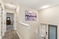 Hall featuring carpet flooring, a textured ceiling, and an upstairs landing - 