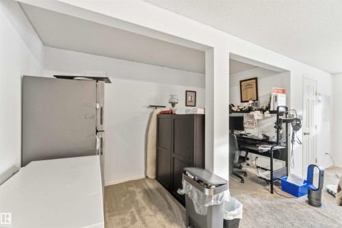 Interior space featuring carpet flooring, freestanding refrigerator, and a textured ceiling - 1706 Turvey Bend, Edmonton, AB - Indoor Photo Showing Other Room