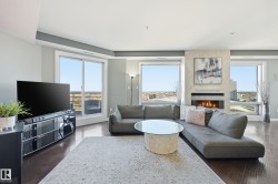 Living room featuring a large fireplace, dark wood-style flooring, and healthy amount of natural light - 