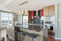 Kitchen featuring stainless steel appliances, modern cabinets, hanging light fixtures, dark wood-style flooring, and a breakfast bar area - 