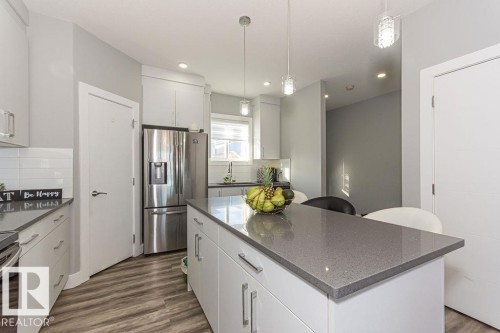 Kitchen with stainless steel fridge, dark stone countertops, dark wood-type flooring, and white cabinets - 1224 Mcconachie Boulevard, Edmonton, AB - Indoor Photo Showing Kitchen With Upgraded Kitchen