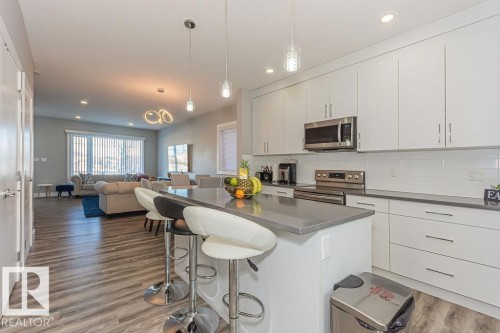 Kitchen featuring a breakfast bar, hanging light fixtures, stainless steel appliances, a kitchen island, and white cabinets - 1224 Mcconachie Boulevard, Edmonton, AB - Indoor Photo Showing Kitchen With Upgraded Kitchen