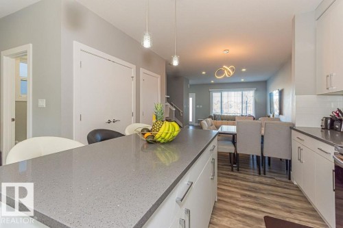 Kitchen featuring white cabinets, dark wood-style flooring, dark stone countertops, and decorative backsplash - 1224 Mcconachie Boulevard, Edmonton, AB - Indoor Photo Showing Kitchen