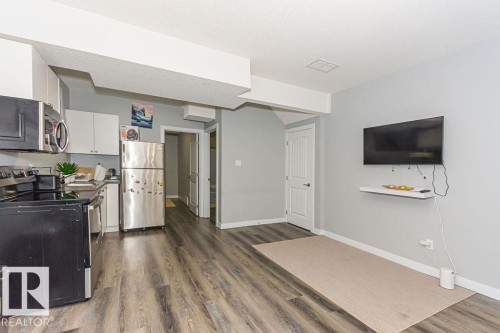 Kitchen featuring stainless steel appliances, white cabinetry, dark wood finished floors, and dark countertops - 1224 Mcconachie Boulevard, Edmonton, AB - Indoor Photo Showing Kitchen