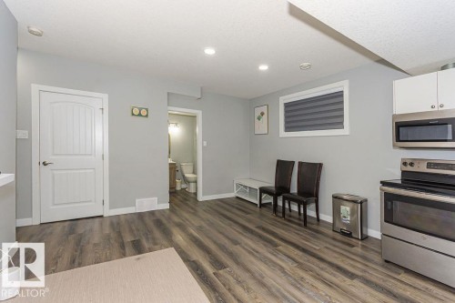 Kitchen with stainless steel appliances, white cabinetry, dark wood-style flooring, and light countertops - 1224 Mcconachie Boulevard, Edmonton, AB - Indoor