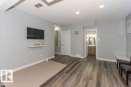 Unfurnished living room featuring dark wood-style floors and baseboards - 1224 Mcconachie Boulevard, Edmonton, AB - Indoor