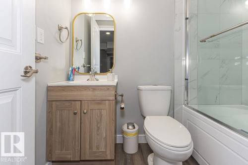 Full bath with enclosed tub / shower combo, vanity, and wood finished floors - 1224 Mcconachie Boulevard, Edmonton, AB - Indoor Photo Showing Bathroom