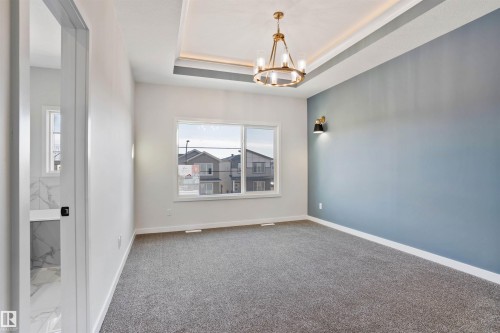 Empty room featuring a tray ceiling, suspended lighting, and carpet - 112 25 Street, Edmonton, AB - Indoor Photo Showing Other Room