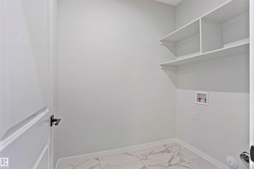 Laundry area featuring washer hookup and light marble finish floors - 112 25 Street, Edmonton, AB - Indoor With Storage