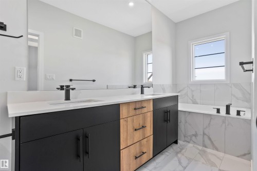 Full bath featuring a bath, double vanity, and light marble finish floors - 112 25 Street, Edmonton, AB - Indoor Photo Showing Bathroom