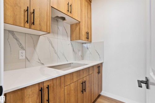 Kitchen with wood finish cabinetry, light stone counters, decorative backsplash, and light wood finished floors - 112 25 Street, Edmonton, AB - Indoor Photo Showing Kitchen