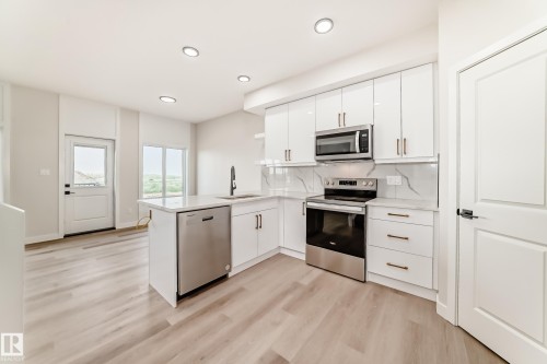 Kitchen featuring stainless steel appliances, white cabinetry, light wood-style flooring, a peninsula, and recessed lighting - 135 Pierwyck Loop, Spruce Grove, AB - Indoor Photo Showing Kitchen