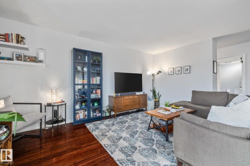 Living area featuring dark wood finished floors and a textured ceiling - 1502 9909 110 Street, Edmonton, AB - Indoor Photo Showing Living Room
