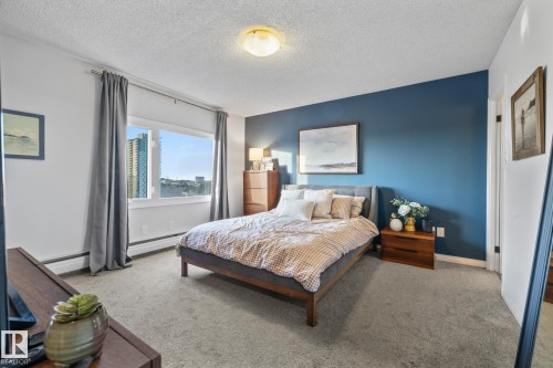 Carpeted bedroom featuring a baseboard heating unit and a textured ceiling - 1502 9909 110 Street, Edmonton, AB - Indoor Photo Showing Bedroom