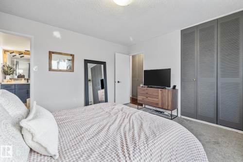 Carpeted bedroom featuring a textured ceiling, a closet, and ensuite bathroom - 1502 9909 110 Street, Edmonton, AB - Indoor Photo Showing Bedroom