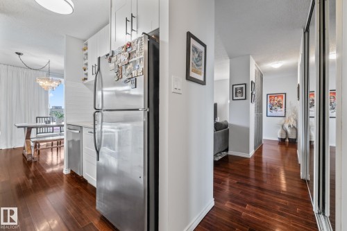 Hall featuring a textured ceiling, dark wood finished floors, and suspended lighting - 1502 9909 110 Street, Edmonton, AB - Indoor Photo Showing Other Room