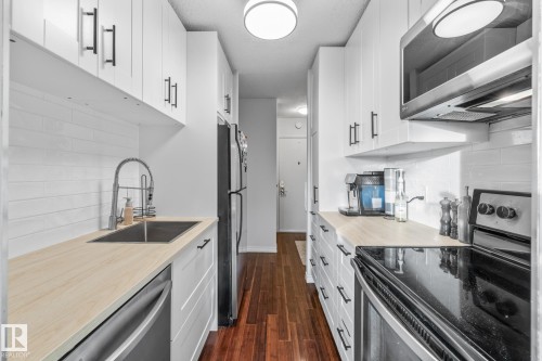 Kitchen featuring stainless steel appliances, light countertops, decorative backsplash, and white cabinets - 1502 9909 110 Street, Edmonton, AB - Indoor Photo Showing Kitchen With Upgraded Kitchen